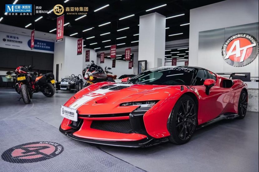 Ferrari on the Xinyate Automobile Group showroom floor beneath the AT emblem wall